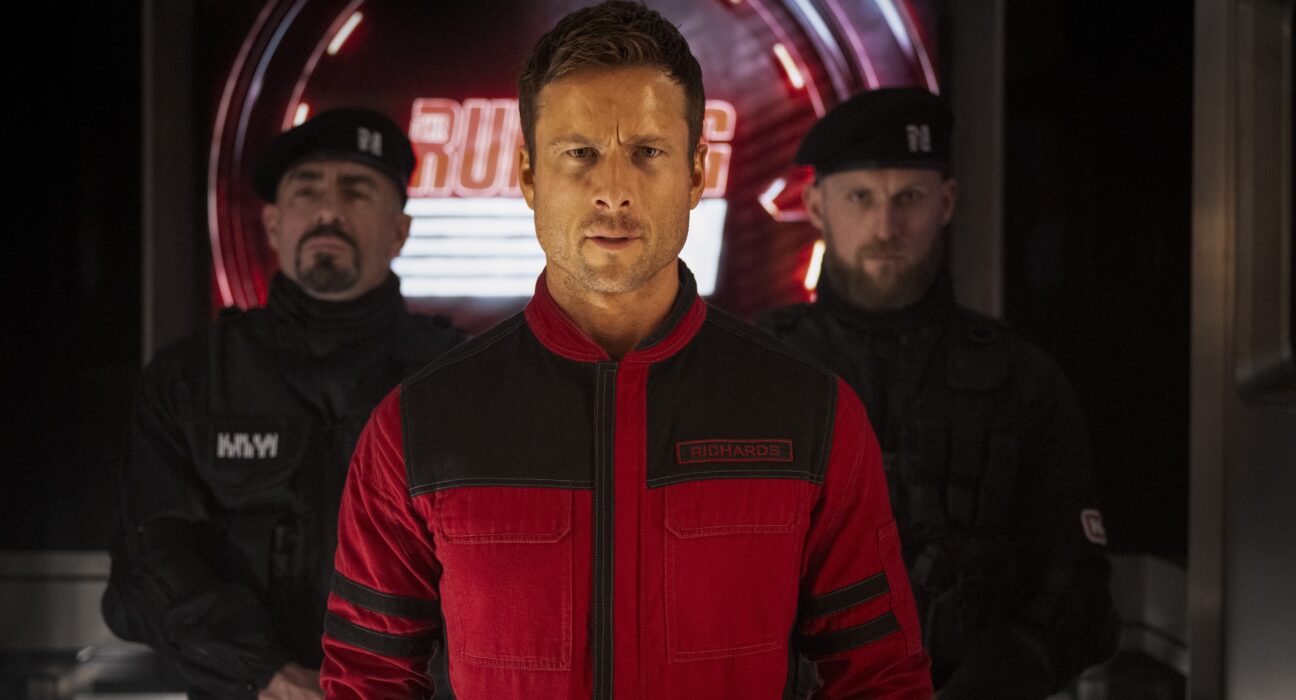 Glen Powell (ao centro) vive Ben Richards na adaptação do livro de Stephen King, 'O Sobrevivente'